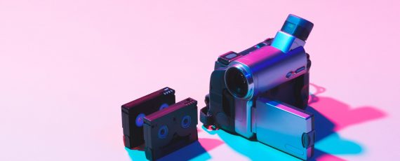 close up view of arranged video cassettes and digital video camera on pink background