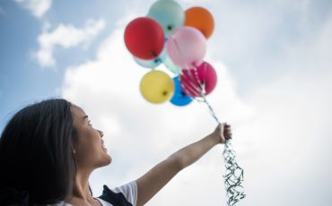 Young girl hand holding colorful balloons